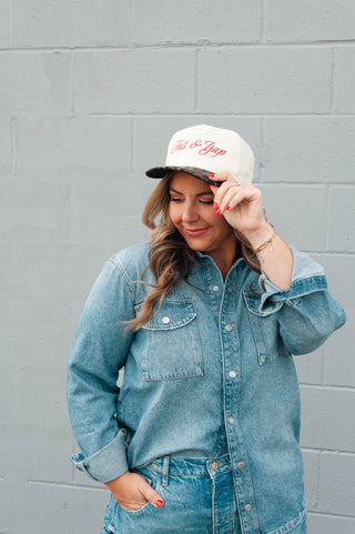 Woman wearing a denim jacket and cap with a gray wall background