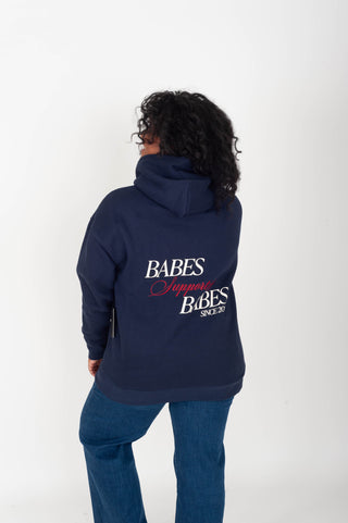 women wearing a navy hoodie with "Babes Supporting Babes" on the back