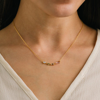 Gold necklace with gemstones on a person wearing a beige top