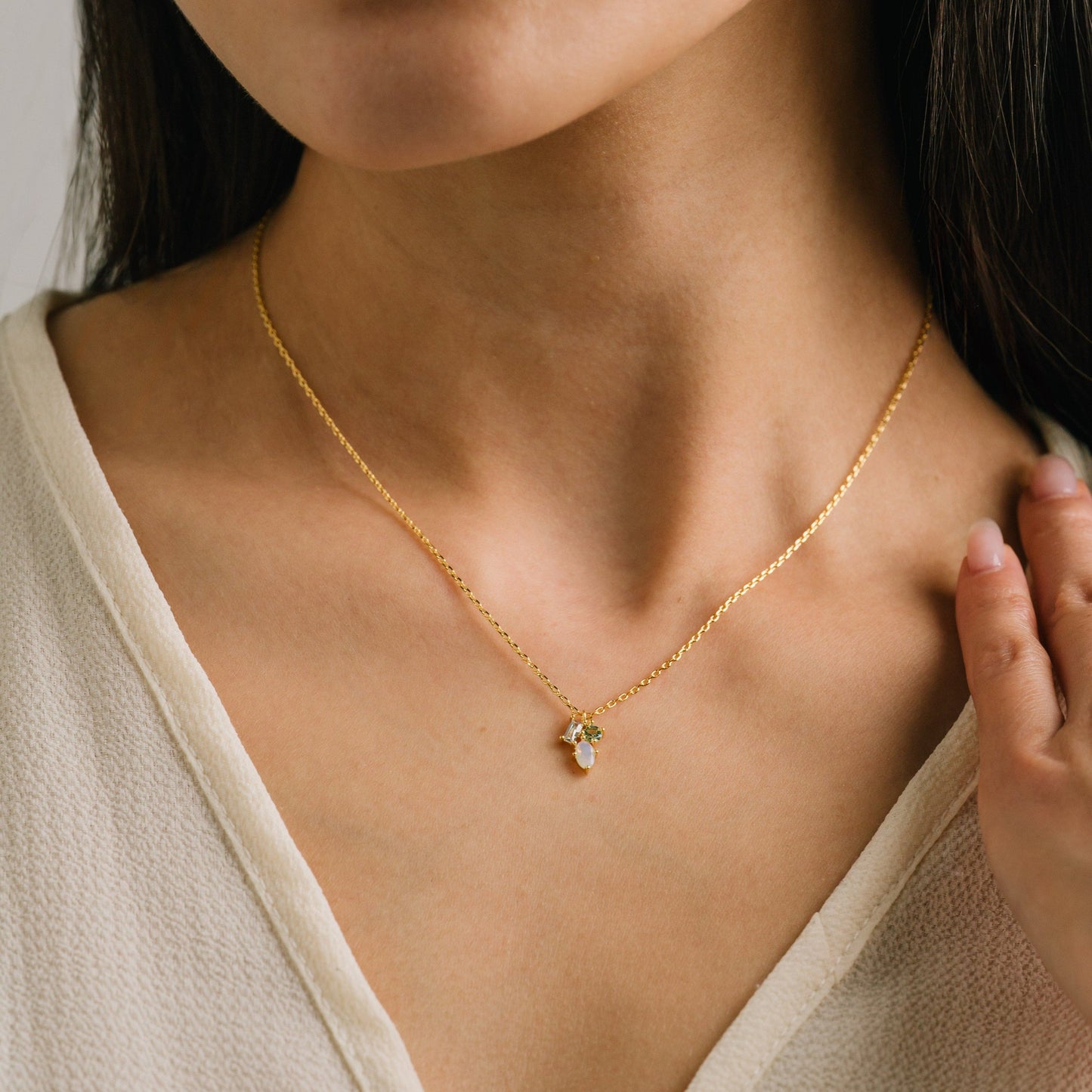 Close-up of a person wearing a gold necklace with a pendant.