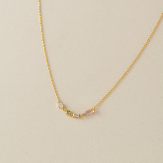 Gold necklace with three small beads on a beige background