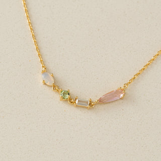 Gold necklace with colorful gemstones on a beige background