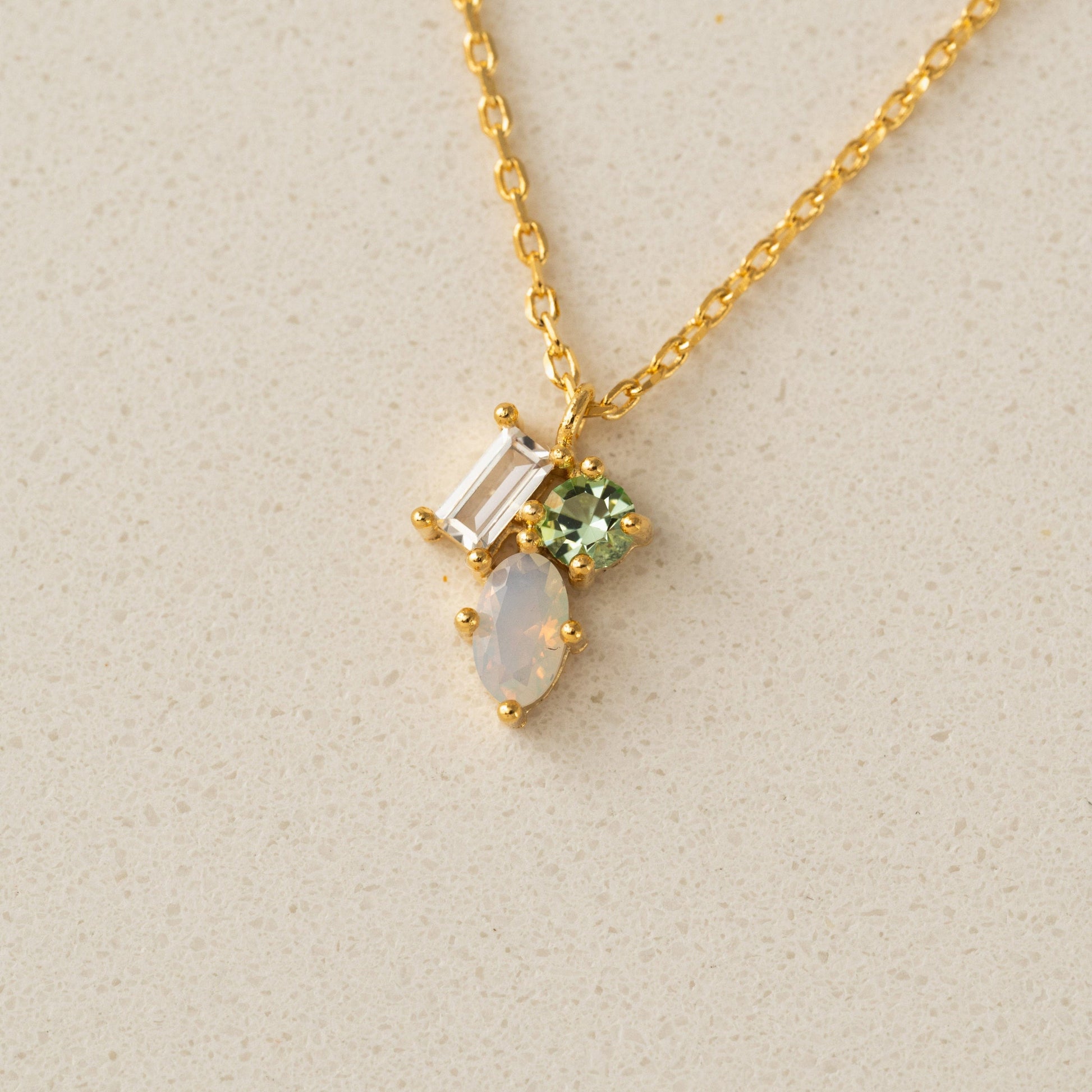 Gold necklace with gemstones on a beige background