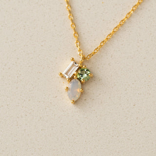 Gold necklace with gemstones on a beige background