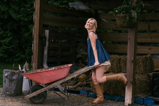 Women carrying a wheel barrel in a denim tunic and cowboy boots