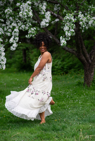 Women wearing a white maxi dress under a cherry blossom tree.