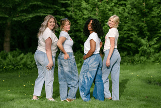 4 women wearing blue jeans and white tops in a garden. 