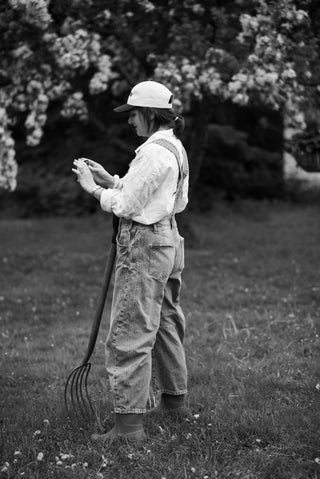 Women wearing overalls and a white blouse holding a pitch fork, 