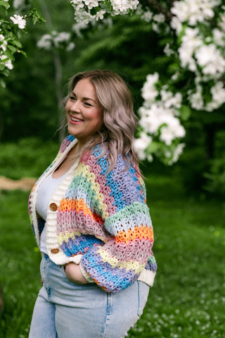 women wearing a rainbow cardigan under a cherry blossom tree