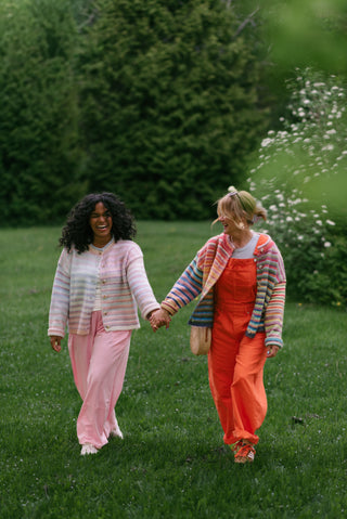 Women wearing rainbow cardigans and bright colour pants in a garden