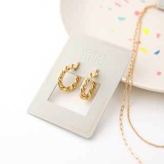 a pair of gold hoop earrings on a branded card