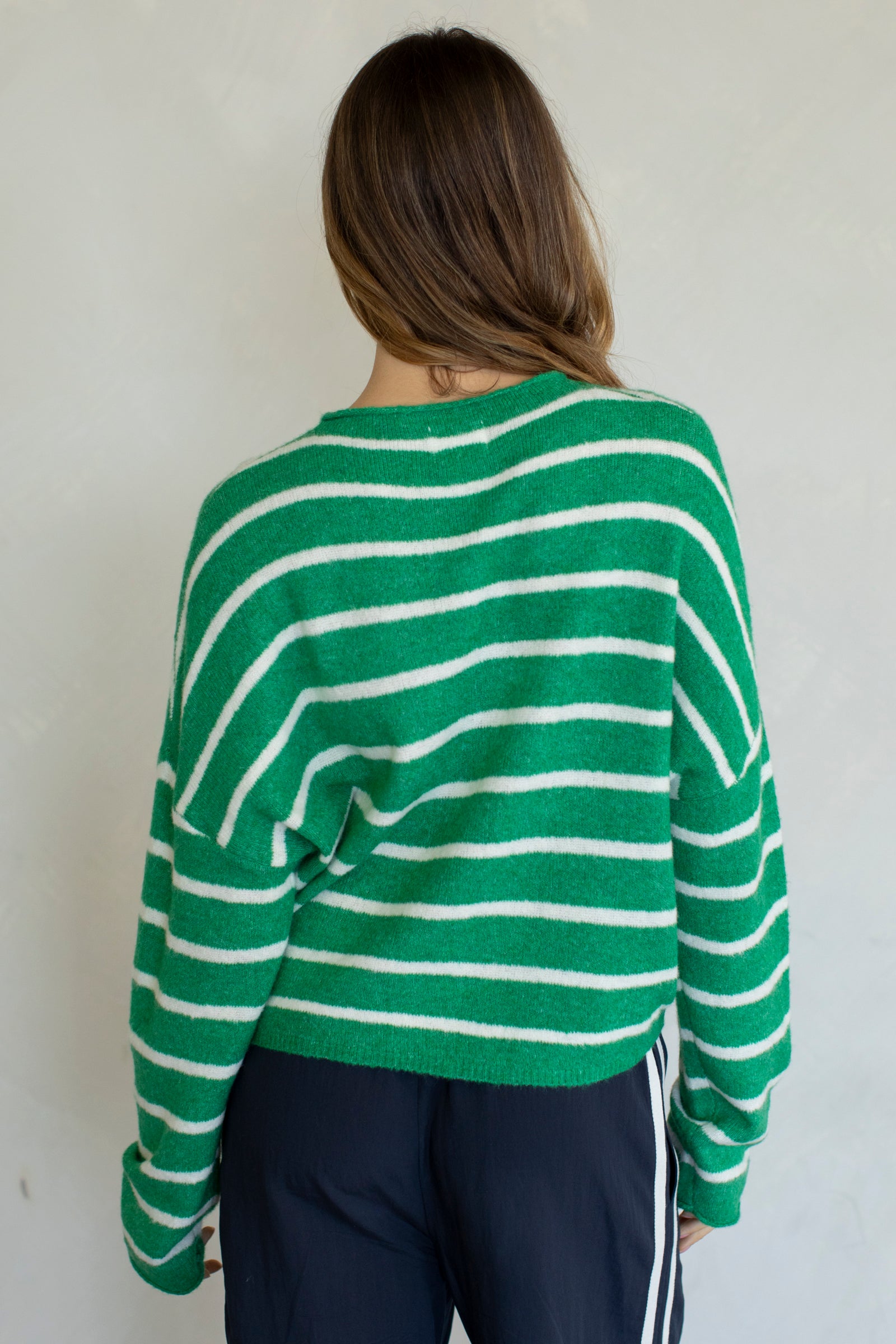Person wearing a green and white striped sweater against a plain background