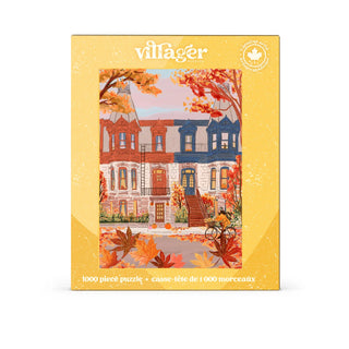 A boxed jigsaw puzzle package on a plain white background. The front shows the brand name "villager" at the top and an illustrated autumn street scene with colorful houses, fall leaves, and warm-toned buildings.