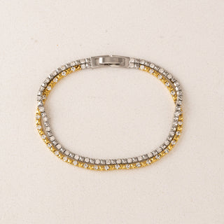 a gold and silver tennis bracelet laying on a table