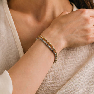 Close-up of a person wearing a bracelet on a neutral background