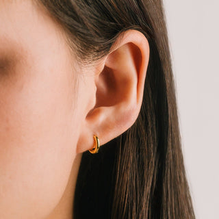 a person wearing gold hoop earrings