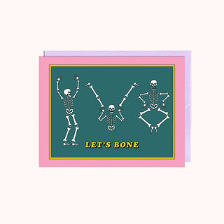 A card with cartoon skeletons on it on a green background with yellow text saying Let's Bone. 