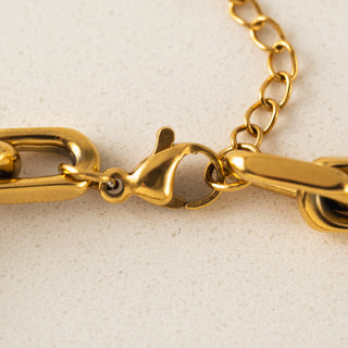 Close-up of a gold chain bracelet on a beige background