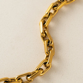 Gold chain bracelet on a beige background