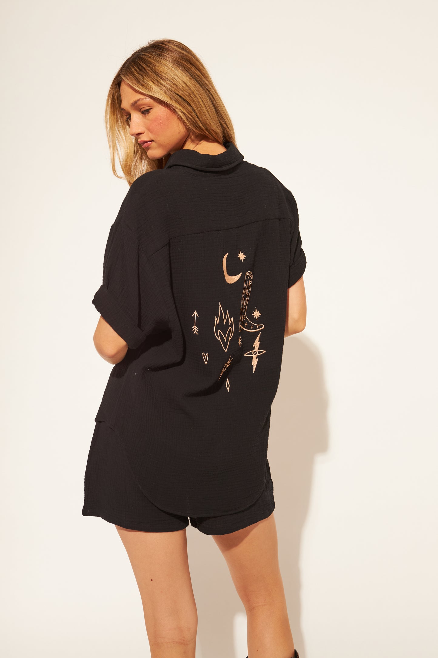 Woman wearing a black shirt with designs on the back against a white background