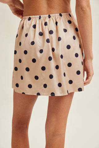 Beige satin skirt with black polka dots worn by a person on a beige background