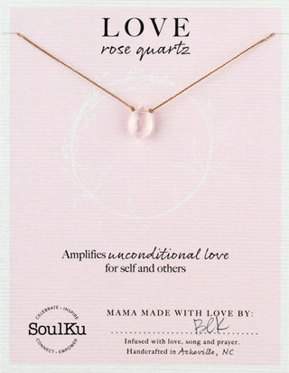 Necklace with rose quartz pendant on a pink card with text about the stone's properties and brand information.