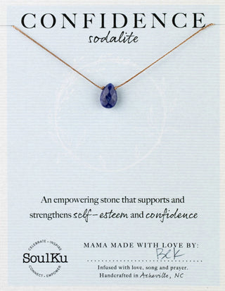 Necklace with a blue pendant on a light blue card with text about the stone's properties and brand information.