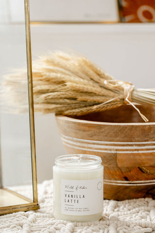 Vanilla latte candle on a textured surface with a decorative basket in the background