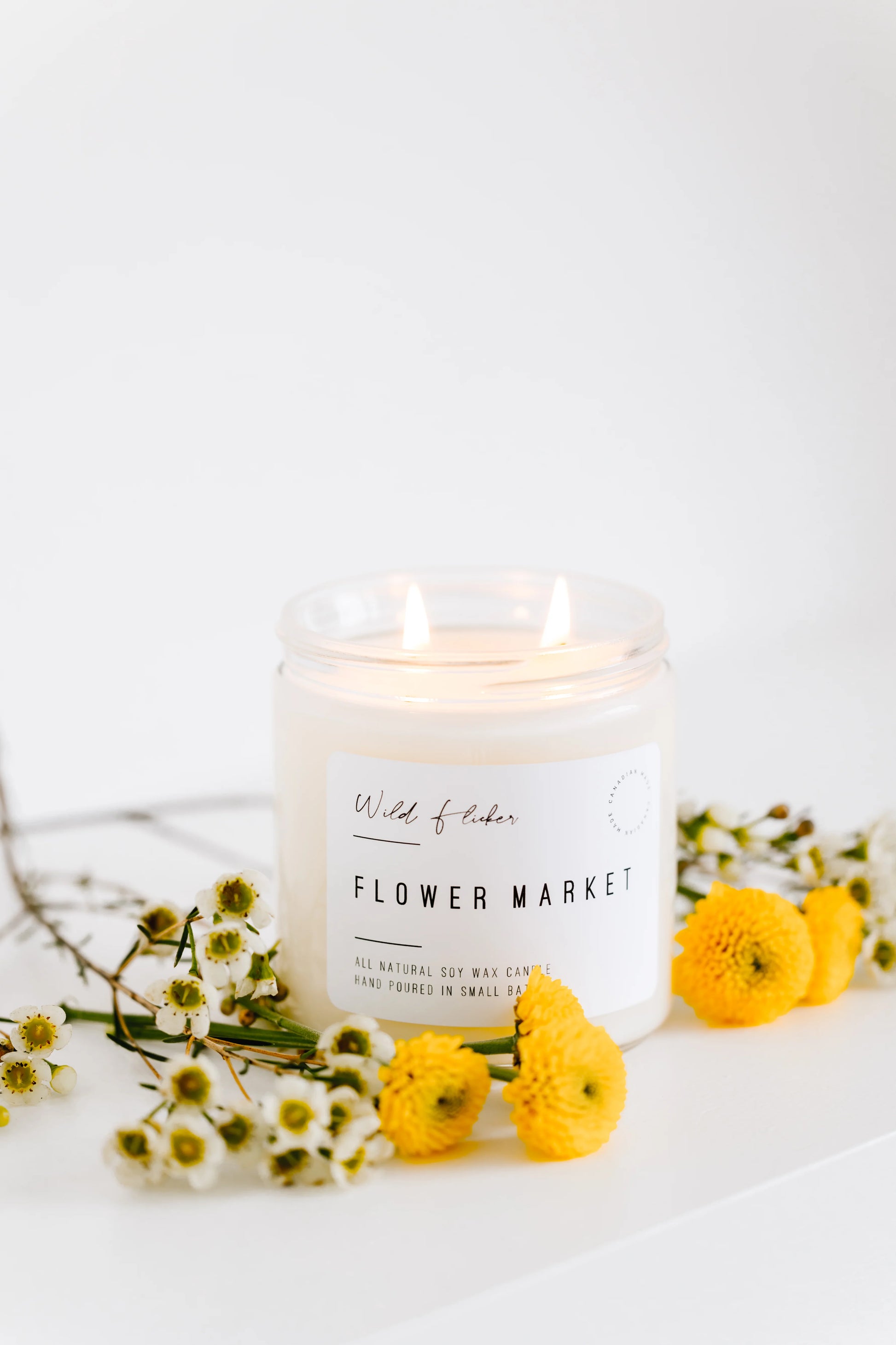 Candle labeled 'Flower Market' with yellow flowers on a white background