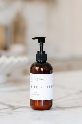 A pump bottle of Milk + Honey hand and body lotion on a marble surface.