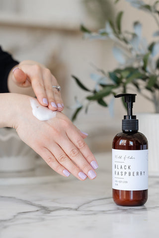 A person's hands being moisturized with a lotion from a pump bottle labeled Black Raspberry.