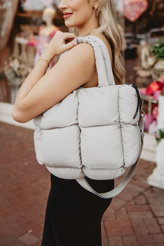 Woman holding a puffer-style backpack in an outdoor setting