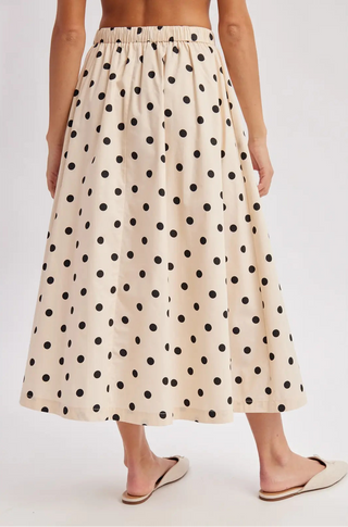 Beige skirt with black polka dots worn by a person on a white background
