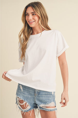 Woman wearing a white t-shirt and denim shorts on a beige background