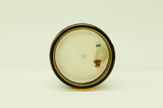 Small glass container with a black rim on a beige background