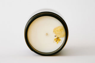 Candle with a flower in a black container on a white background