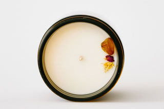 Candle in a black container with dried flowers on a white background