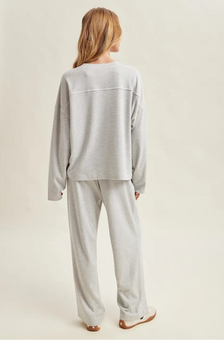 Person wearing a gray pajama set on a beige background
