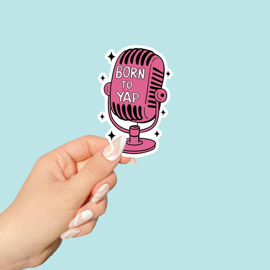 Sticker of a pink microphone with 'Born to Yap' text held by a hand against a light blue background