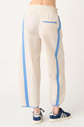 Beige pants with blue stripes worn by a person on a white background