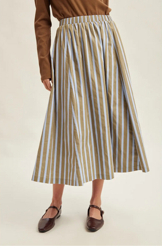 A women wearing a striped skirt against a neutral background.