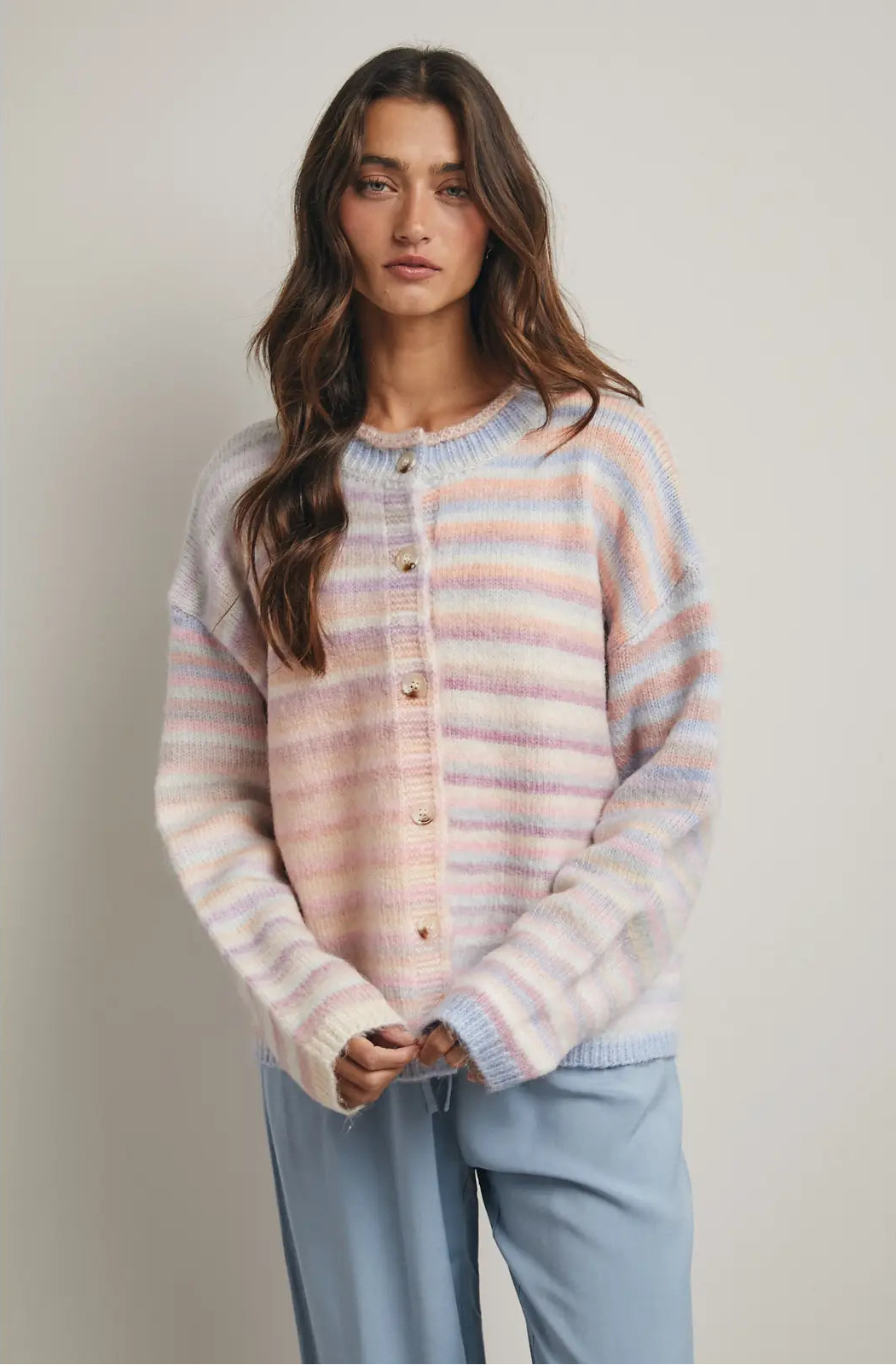 Women wearing a pastel cardigan on a plain background. 