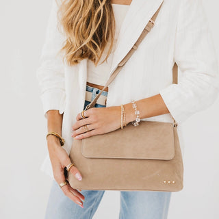 Women wearing a taupe crossbody bag against a white photo background.