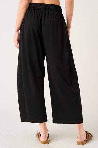 Person wearing black wide-leg pants on a white background