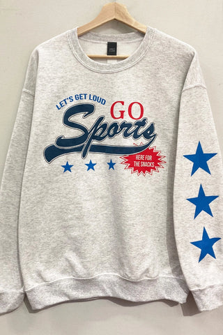 A light heather gray crewneck sweatshirt hanging on a wooden hanger against a plain wall. The sweatshirt features a patriotic sports graphic on the front with 'LET'S GET LOUD GO Sports' in red and navy blue, and three blue stars printed down the right sleeve.