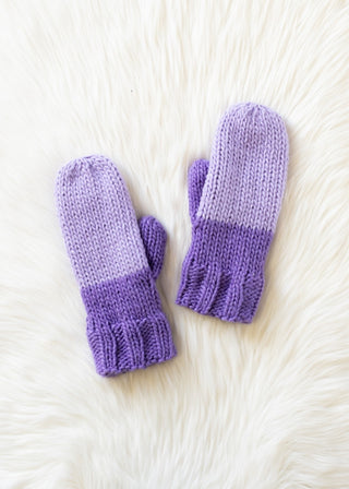 Pair of purple knit mittens on a white textured surface