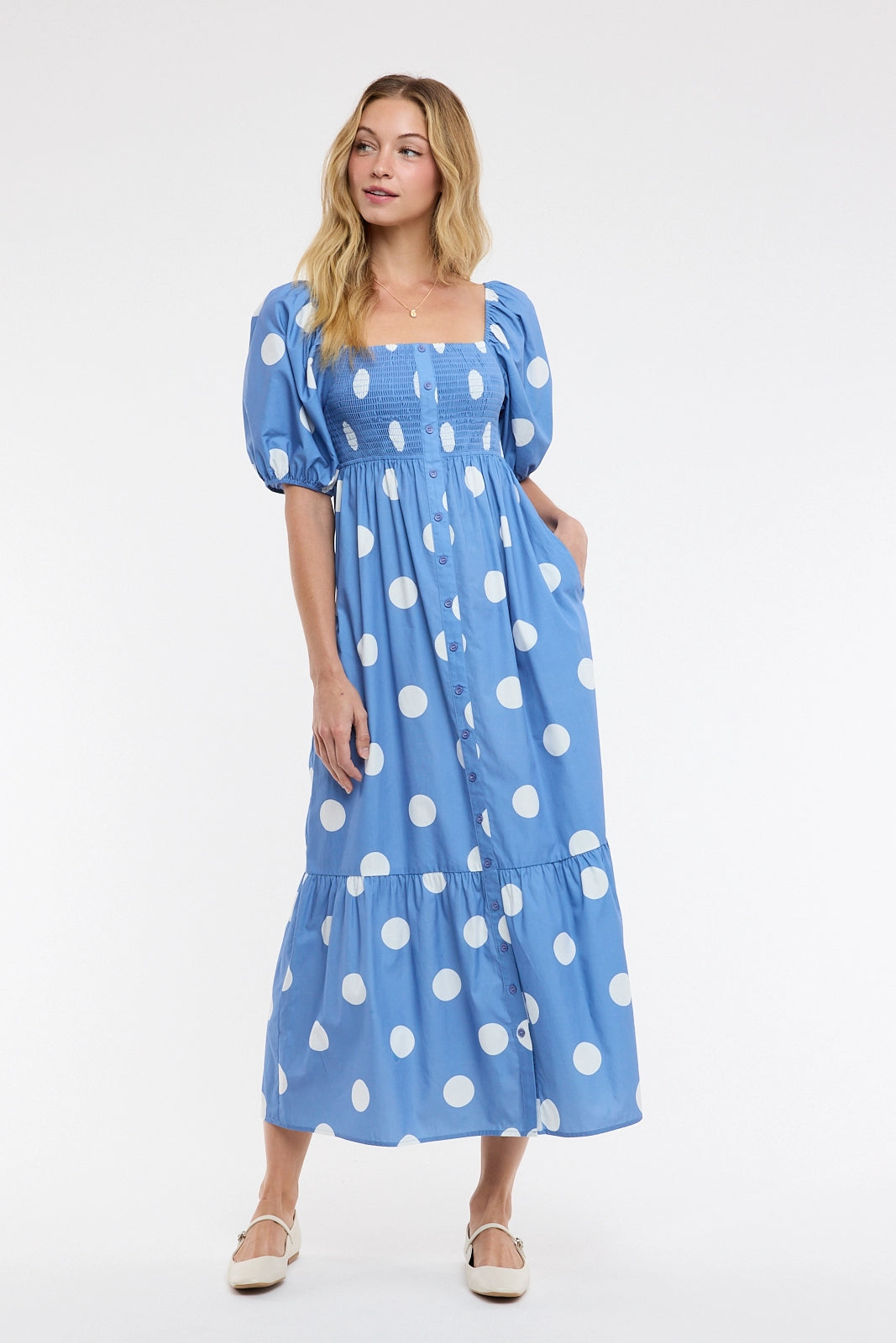 women wearing a blue and white polka dot maxi dress on a white background.