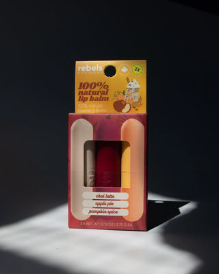 Packaged lip balm with 'rebels' branding on a dark background