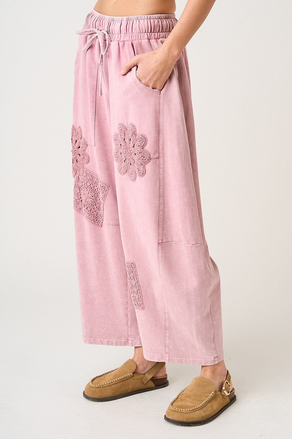 Pink pants with floral embroidery worn by a person on a white background