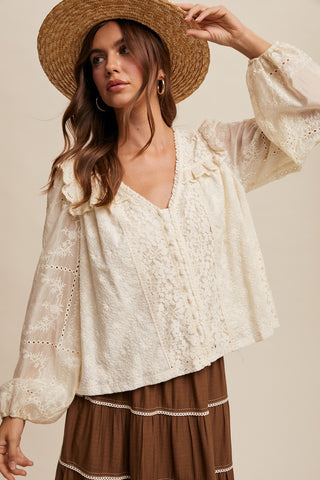 Woman wearing a lace blouse and straw hat against a beige background